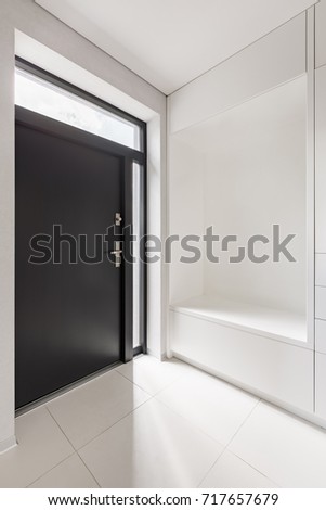 Elegant home interior with white entryway and black door