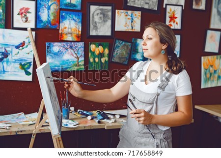 Portrait of young beautiful middle age white Caucasian woman artist drawing painting in art studio with acrylic paints on canvas. Lifestyle activity hobby concept