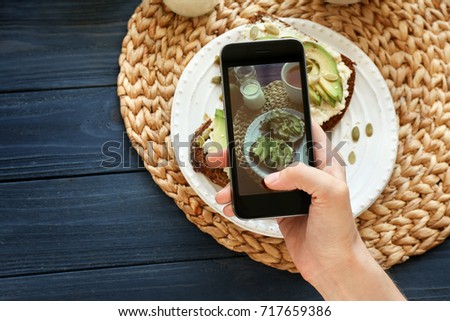 Young woman taking photo of delicious toasts with mobile phone