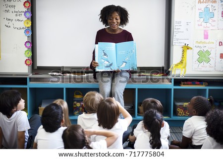 Kindergarten students sitting on the floor listening to story telling Royalty-Free Stock Photo #717775804
