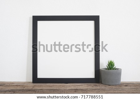 Black square frame poster with cactus pot on wooden shelf