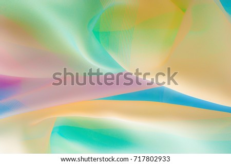 Blurry, not sharp sharpness Texture, background, pattern. Silk fabric is transparent, yellow-pink green in blue. Abstract soft chiffon texture background. 