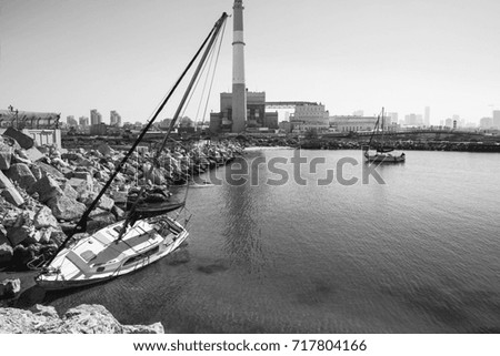 Yacht floating on the side after the crash in the port of Tel Aviv. Breakwater protecting of power station in Israel. Black and white picture