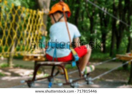 The boy climbs a pendant park blurred abstract background