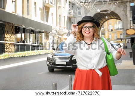 Beautiful stylish overweight woman with hat on street
