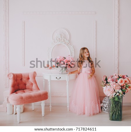 Little cute princess girl in pink dress in pink room.