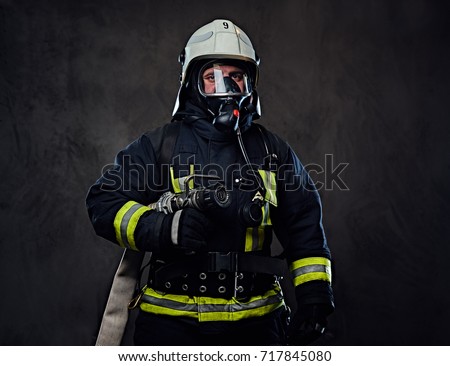 Studio portrait of firefighter dressed in uniform and an oxygen mask.