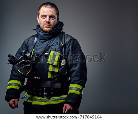 Studio portrait of a male dressed in a firefighter uniform holds an oxygen mask.