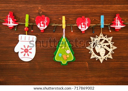 Wooden and felt Christmas decorations and Christmas lights on a rope on the brown wooden background, top view.