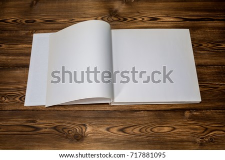 Photo of blank opened brochure magazine on wooden background with soft shadows. Mock-up for graphic designers portfolios.