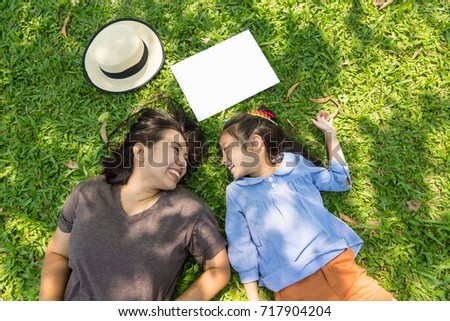 Asian mother and daughter enjoy picnic outdoor and lying on grass, concept of family Royalty-Free Stock Photo #717904204
