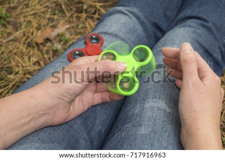 trendy fidget spinner - person holding  spinning fidget spinner in hand, close up view