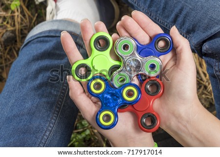 trendy fidget spinner - person holding  spinning fidget spinner in hand, close up view