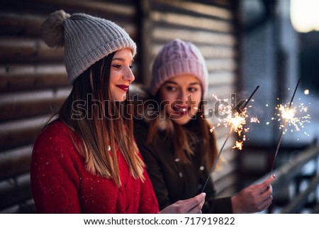 Photo of two women holding sparkling sticks.