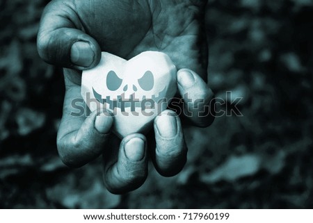 Potato heart with Halloween face in the rough male hands 