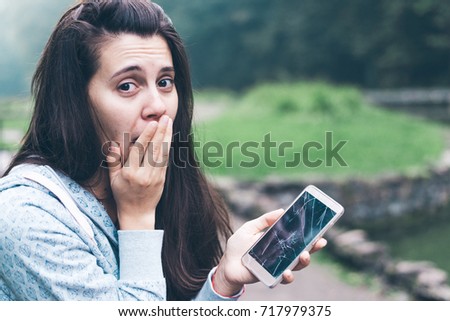 sad woman sitting on the bench with cracked phone