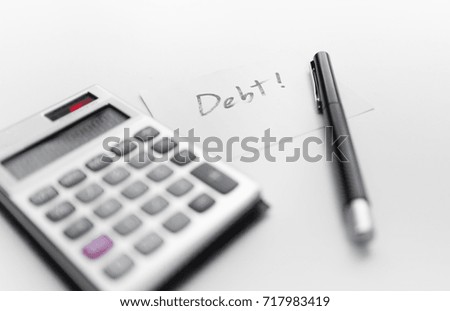calculator with a pen and paper note with word debt isolated on white background
