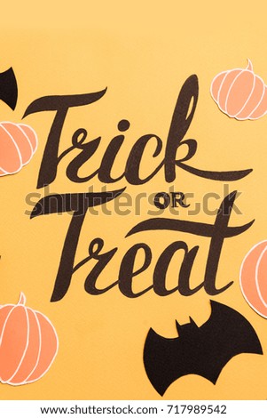Haloween theme phrase in frame of pumpkins and bats on orange background