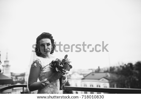 The bride is standing on the balcony with a bouquet