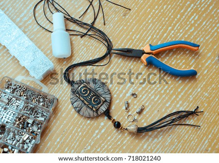 Assembly of  boho pendant with pliers and tools on wooden background. Enjoy hobby. Tools for handicraft. Jewelry from polymer clay.