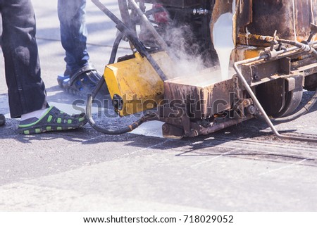 Workers painting white lines on the street.By painting machine .
