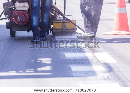 Workers painting white lines on the street.By painting machine .