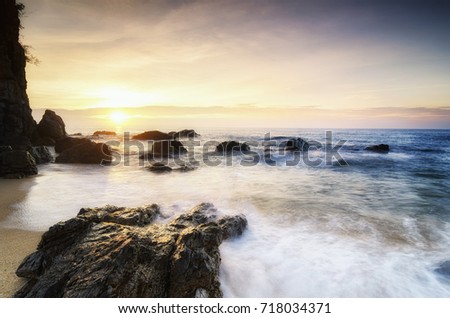 Travel and leisure concept, beautiful sea view scenery over stunning sunrise background.sunlight beam and soft wave hitting beach rocks