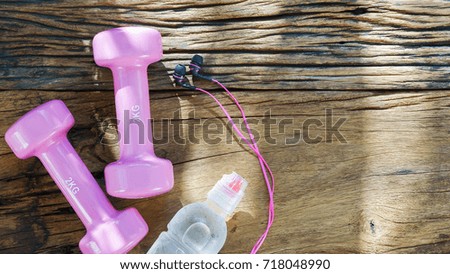 Fitness, healthy and active lifestyles Concept, pink dumbbells, bottle of water, earphones on wood background. top view with blank copy space