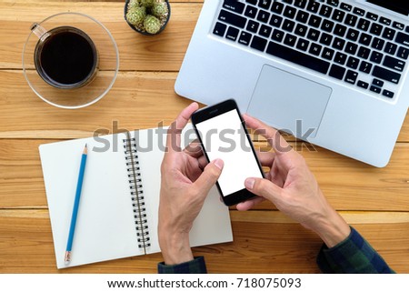 Man hands holding blank screen a smartphone on work desk.