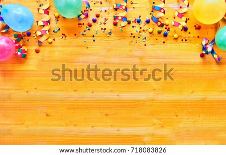 Carnival concept of balloons, ribbons, confetti against wooden background with copy space