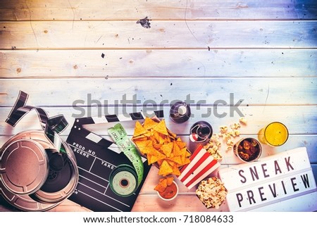 Overhead view of brightly lit metal large film reel and rolled up tickets and food and drinks and lettered sign