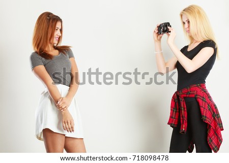 Photographer and model. Blonde girl shooting images, taking photos with camera, photographing female model