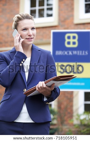 Female Realtor On Phone Outside Residential Property For Sale