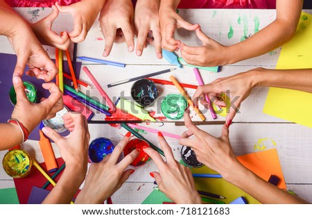 Art and craft concept. Artists hands with stationery and paper. Art supplies and hands showing victory and heart signs on white background, top view. Hands hold colorful markers, pencils and paints
