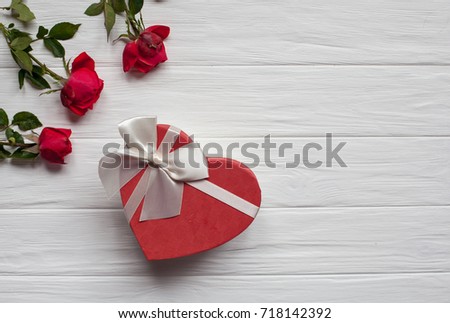 red roses isolated in white wooden background, gift box with white ribbon. hearts confetti. flat lay. space for your text.
