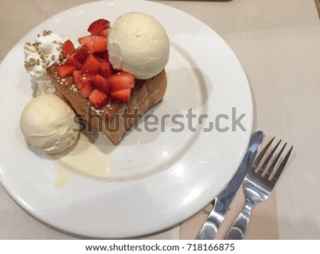 Sweet strawberry toast with ice cream on white plate.
