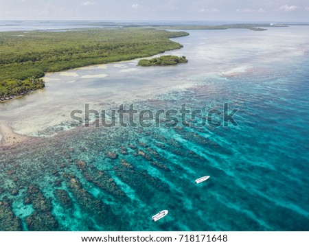 An aerial view of the barrier reef along Turneffe Atoll in Belize reveals spur and groove channels that exist near shore. This type of reef often develops on windward sides of islands. Royalty-Free Stock Photo #718171648