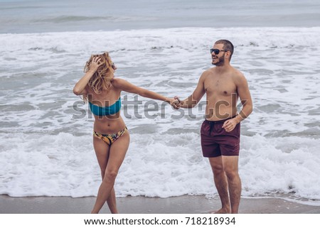 Beautiful young attractive and modern couple enjoying on the beach in warm summer day