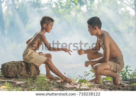 Two little boys sitting on a floor, play - Rock, Paper, Scissors, in  Thailand.
