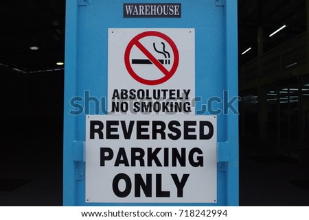 Combination of signs related to smoking policy and parking rule.