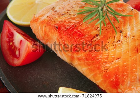 food: grilled salmon on iron pan over wooden plate isolated on white background
