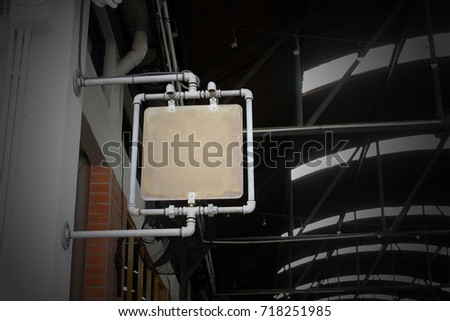 Horizontal front view of empty square vintage steel plate rust signage on a side of building hanging with steel pipe.