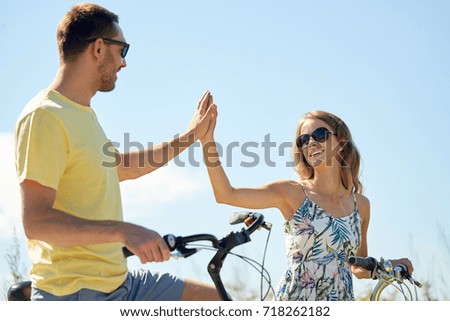 people, leisure and lifestyle concept - happy young couple with bicycles at country making high five