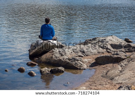  Nice picture of a man sitting on a cliff looking out to the lake, river or sea. Yoga mediation.