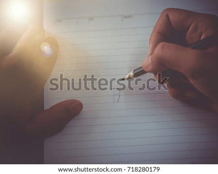 female hands with pencil writing on notebook