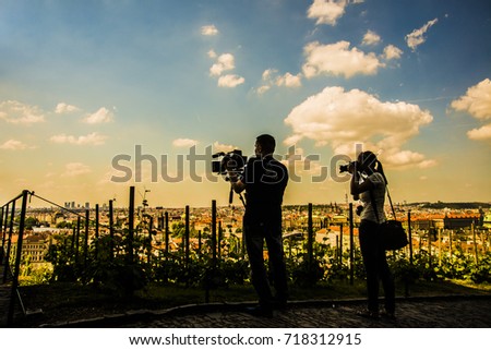 back silhouette of Photographer woman and Videographer man working against blue sky and Prague city town, Czech Republic. wedding time