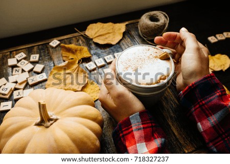 Pumkin latte wooden blocks against a rustic wood background with woman hands, coffee, pumpkins and autumn leaves