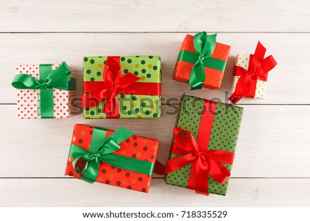 Gift boxes in colorful dotted paper decorated with satin ribbon bows on white wooden background. Presents for christmas, valentine day or birthday, top view, copy space