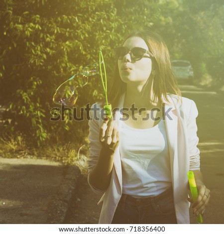 Young pretty girl blows bubbles, outdoor
