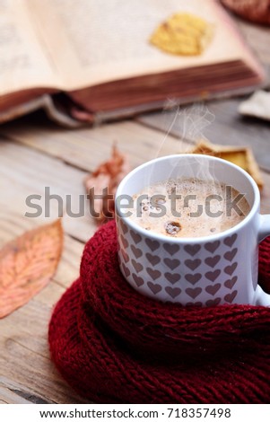 Cup hot cappuccino coffee on wooden table with autumn leaves ,book.Autumn mood concept.Warm autumn picture .Selective focus.